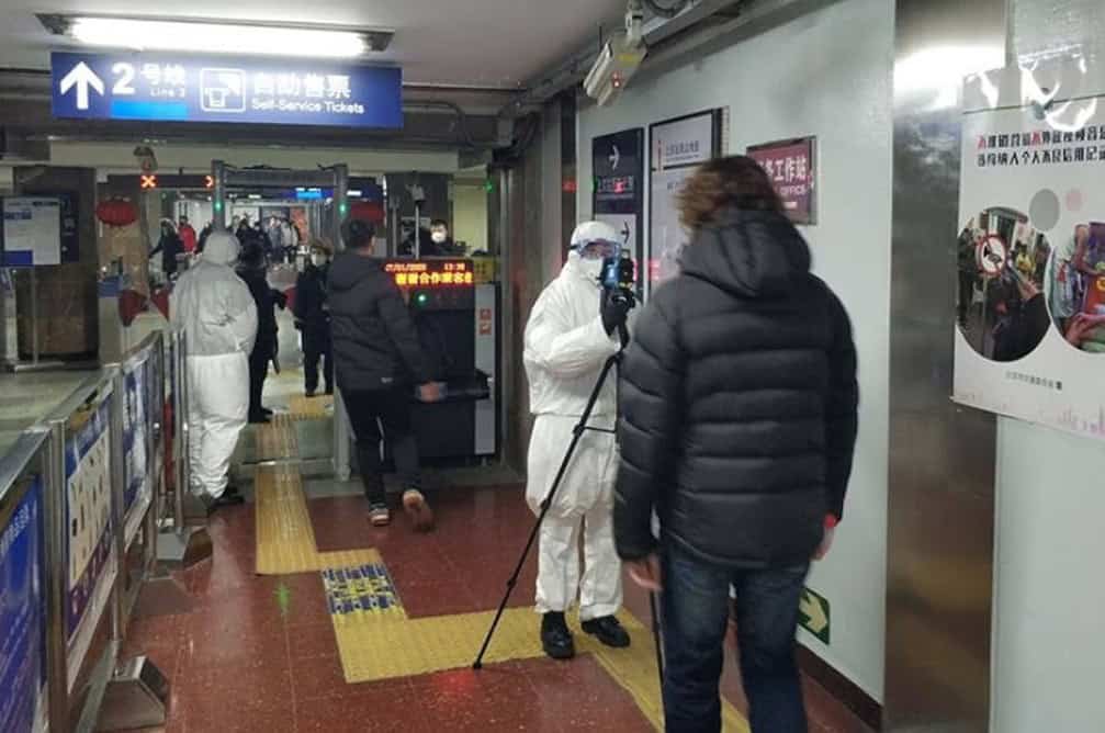 People in hazmat suits taking photos of passengers about to board onto a train for covid precautions