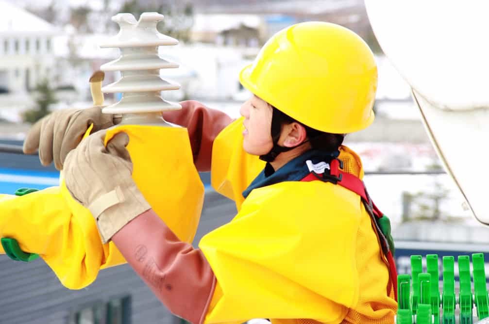 An engineer in high visibility equipment and a hard hat working with a piece of machinery