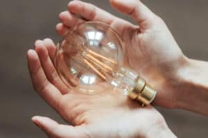 Two hands holding a lightbulb