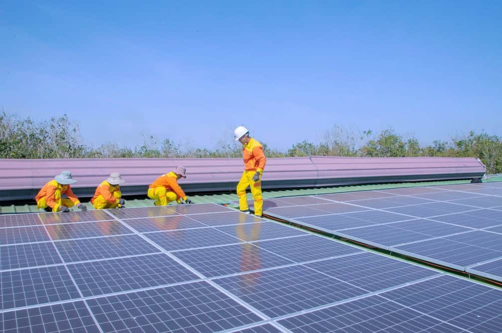 A group of men in high visibility uniforms working on solar panels