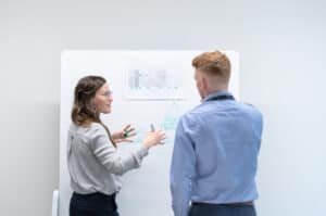 Woman explaining a diagram on a white board to a man