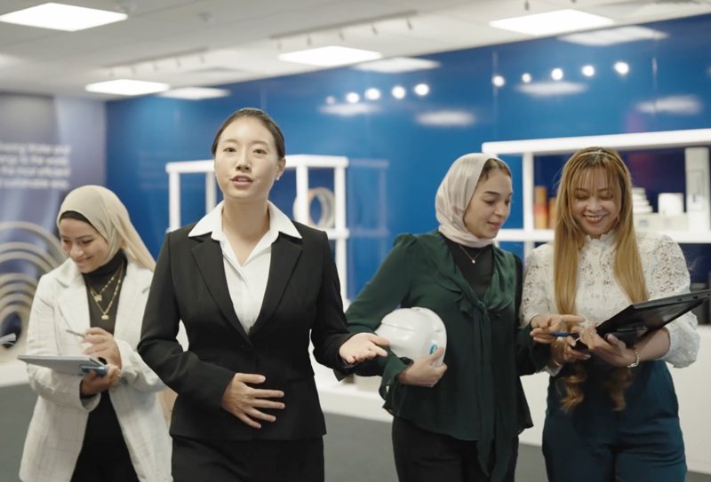 Four women in business attire walk through an office, discussing and reviewing notes on tablets. Their conversation revolves around Future Pipe Industries, exploring innovations in the pipe manufacturing sector and how industrial pipes can revolutionize infrastructure.