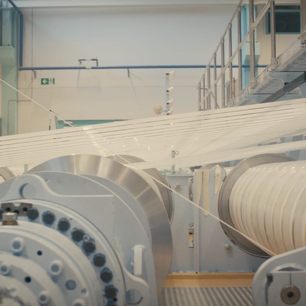 Albany International's industrial machine features large cylindrical reels and thin strings weaving intricately across.