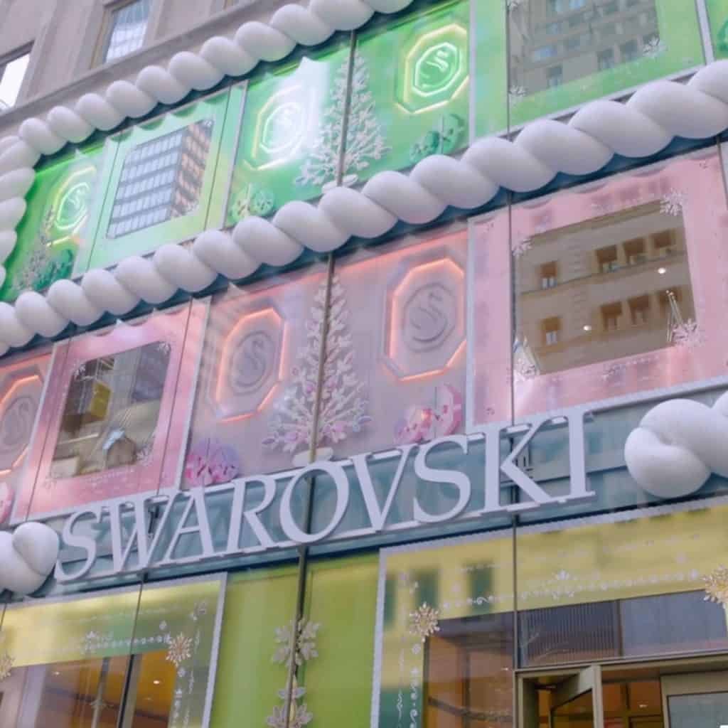 Storefront with pastel festive decorations featuring the Swarovski logo. Displays include geometric patterns and snowflakes.