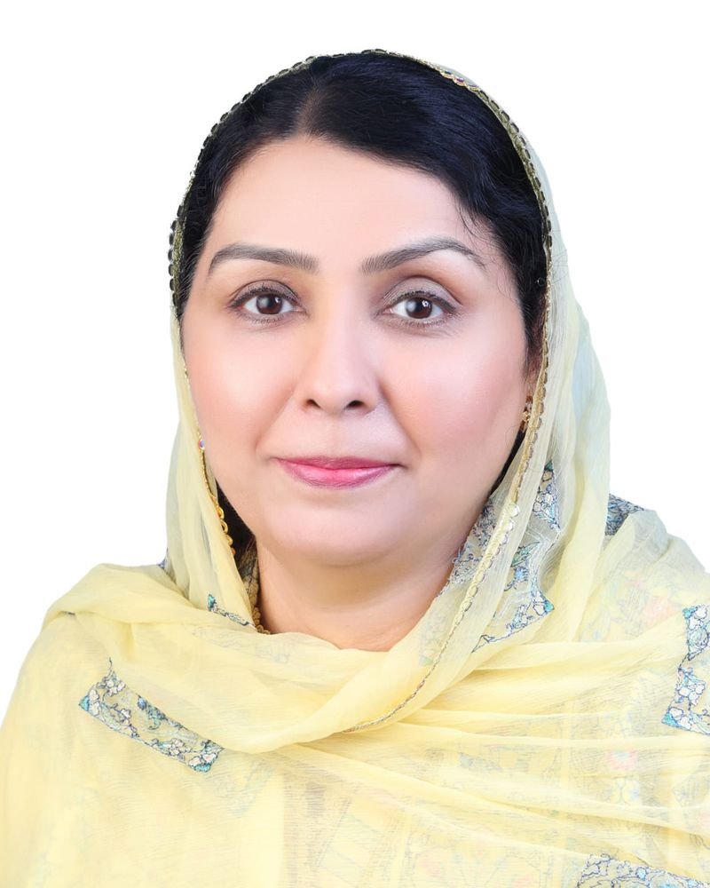 Prof. Dr. Khadija Qureshi, in a light yellow headscarf and top, gazes confidently at the camera against a pristine white background.